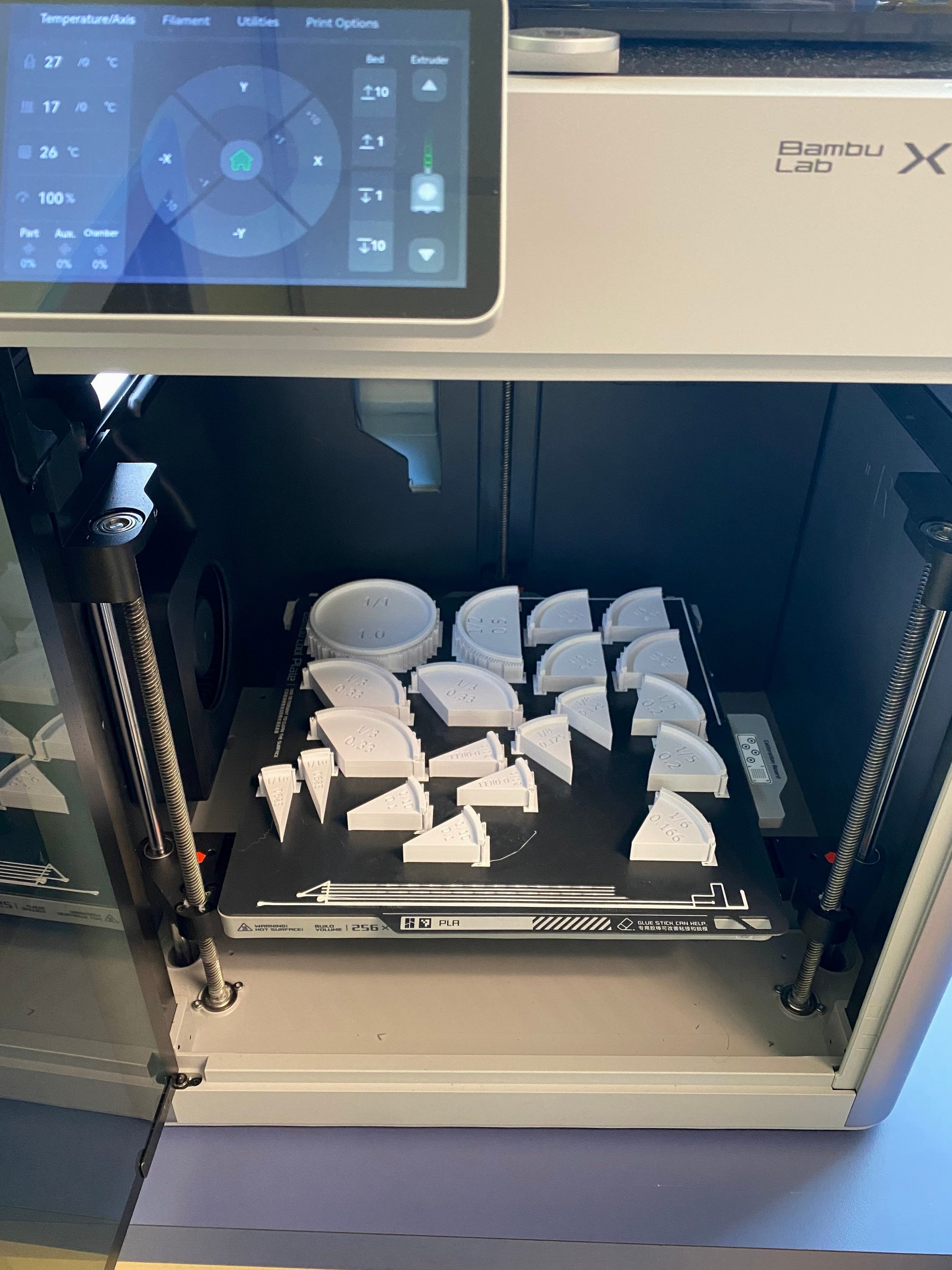 A Bambu Lab 3D printer with a full bed of freshly printed fraction manipulatives.